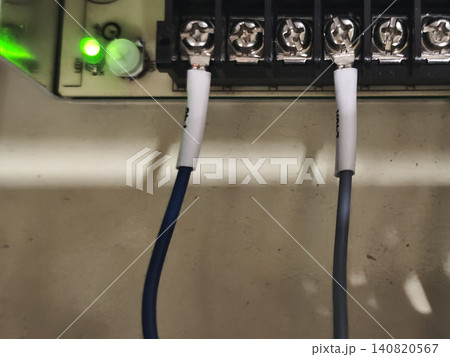 Electrical terminal block with connected wire, green indicator light on control panel, close up of industrial wiring installation Electrical terminal block with connected wire, green indicator light on control panel, close up of industrial wiring installation 140820567