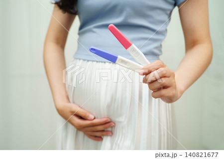 Asian holding pregnancy test for female of ovulation day, fetus, maternity, childbirth, birth control. Asian holding pregnancy test for female of ovulation day, fetus, maternity, childbirth, birth control. 140821677