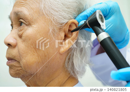Otolaryngologist or ENT physician doctor examining senior patient ear with otoscope, hearing loss problem. Otolaryngologist or ENT physician doctor examining senior patient ear with otoscope, hearing loss problem. 140821805