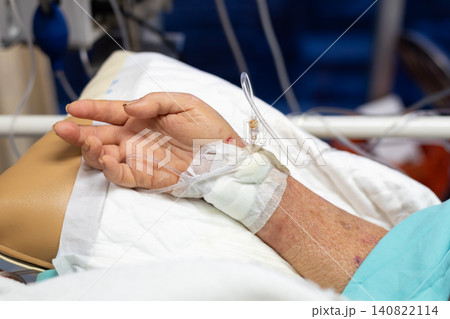 Closeup of patient hand intravenous catheter hospital bed receiving medical treatment healthcare emergency recovery nursing care clinical monitoring Closeup of patient hand intravenous catheter hospital bed receiving medical treatment healthcare emergency recovery nursing care clinical monitoring 140822114