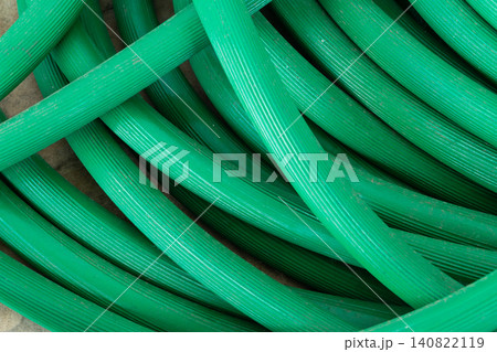 Closeup of coiled green garden hose textured surface creating abstract industrial background suitable for gardening irrigation plumbing maintenance utility concepts Closeup of coiled green garden hose textured surface creating abstract industrial background suitable for gardening irrigation plumbing maintenance utility concepts 140822119