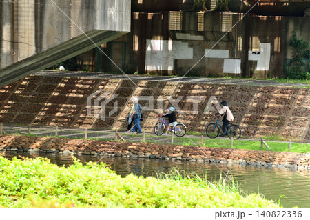 旧中川に架かる鉄橋の下を歩く人と自転車に乗る人 140822336