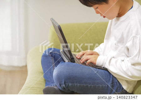 ソファに座ってパソコン学習をする子ども ソファに座ってパソコン学習をする子ども 140823347