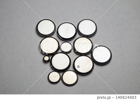 Flat round batteries of different sizes on a gray background Flat round batteries of different sizes on a gray background 140824883