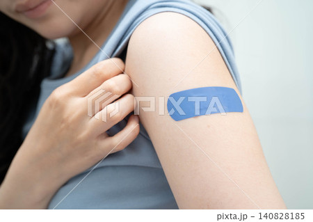 HPV, Human papillomavirus, Asian young woman receiving vaccine with blue bandage. HPV, Human papillomavirus, Asian young woman receiving vaccine with blue bandage. 140828185