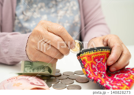 Asian senior or elderly old lady woman holding counting coin money in bag. Poverty, saving problem in retirement. Asian senior or elderly old lady woman holding counting coin money in bag. Poverty, saving problem in retirement. 140828273