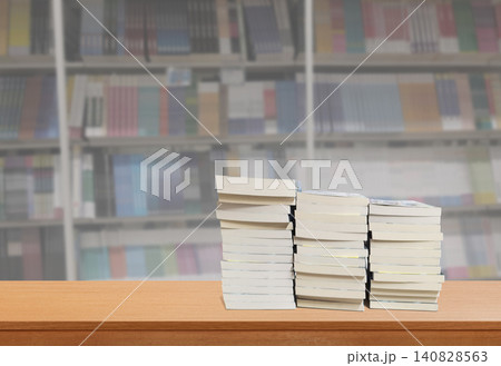 Several books lay on a wooden table inside the library. Several books lay on a wooden table inside the library. 140828563