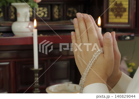 仏壇の前で手を合わせて祈る女性 仏壇の前で手を合わせて祈る女性 140829044