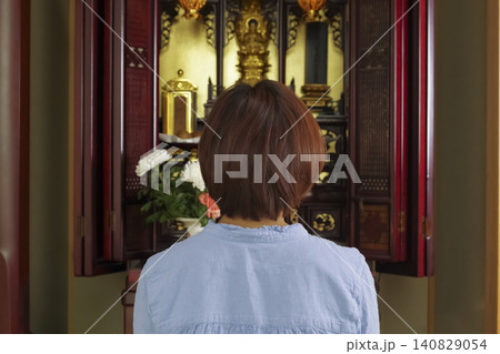 仏壇の前で手を合わせて祈る女性 140829054