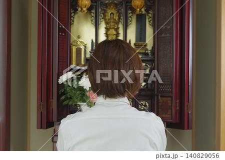 仏壇の前で手を合わせて祈る女性 仏壇の前で手を合わせて祈る女性 140829056