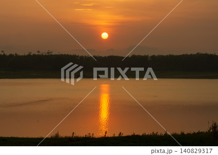 Golden sunset over a calm lake with sun reflection on water surface and forest silhouette Golden sunset over a calm lake with sun reflection on water surface and forest silhouette 140829317