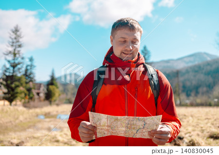 Young man tourist holding paper map and pointing forward in mountains Young man tourist holding paper map and pointing forward in mountains 140830045