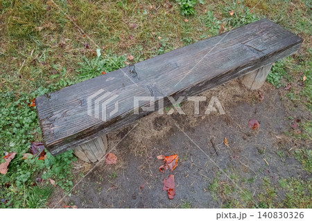 草地に置かれた古い木製ベンチと落ち葉 草地に置かれた古い木製ベンチと落ち葉 140830326