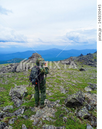 Hiker with backpack and trekking poles on the top of the mountain 140830445
