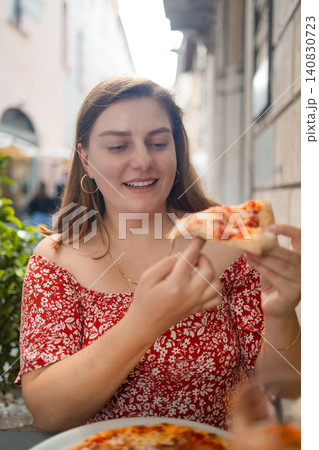 Happy young woman eating delicious Italian pizza at outdoor cafe in Europe Happy young woman eating delicious Italian pizza at outdoor cafe in Europe 140830723