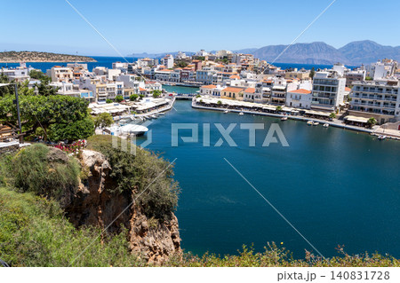 High angle panoramic view of Lake Voulismeni with rocky cliff and seaside town architecture in Agios Nikolaos, Crete, Greece High angle panoramic view of Lake Voulismeni with rocky cliff and seaside town architecture in Agios Nikolaos, Crete, Greece 140831728