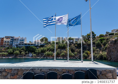 National flag of Greece European Union flag and Agios Nikolaos municipality flag on masts at Lake Voulismeni port, Crete, Greece National flag of Greece European Union flag and Agios Nikolaos municipality flag on masts at Lake Voulismeni port, Crete, Greece 140831737