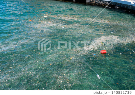 Plastic pollution and floating garbage scum in the sea water near a concrete pier Plastic pollution and floating garbage scum in the sea water near a concrete pier 140831739