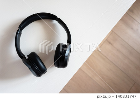 Black wireless in-ear headphones at home on the wood table. New digital technologies. Earphones and space for text. 140831747