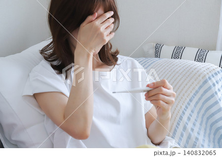 体温計で熱を測る体調不良の女性 体温計で熱を測る体調不良の女性 140832065
