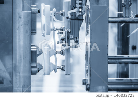 Industrial robotic arm gripping and removing plastic parts from an injection molding machine. 140832725