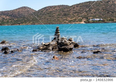 Balanced pebble rock tower cairn on the rocky seashore of Mirabello Bay in Elounda, Crete, Greece 140832866