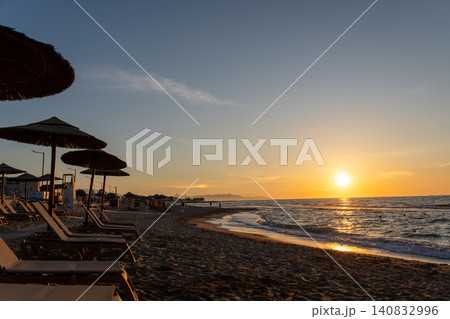Beautiful golden sunset over resort beach with silhouettes of umbrellas Beautiful golden sunset over resort beach with silhouettes of umbrellas 140832996
