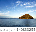 穏やかな青い海に浮かぶ三角形の小島と秋色の木々・青空の絶景 140833255