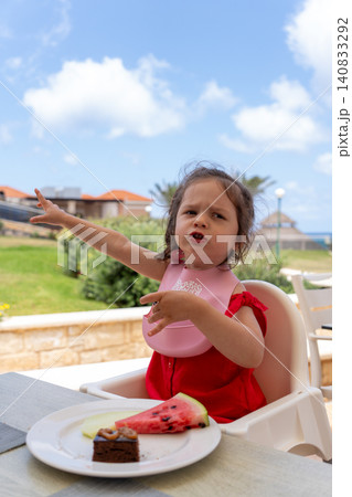 Vertical portrait of toddler girl pointing away at outdoor restaurant Vertical portrait of toddler girl pointing away at outdoor restaurant 140833292