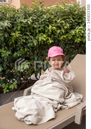 Vertical portrait of cute toddler girl wrapped in towel on sunbed Vertical portrait of cute toddler girl wrapped in towel on sunbed 140833300
