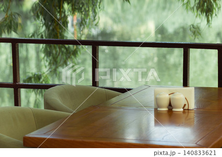 Empty restaurant table with willow branches over a blurred river background Empty restaurant table with willow branches over a blurred river background 140833621
