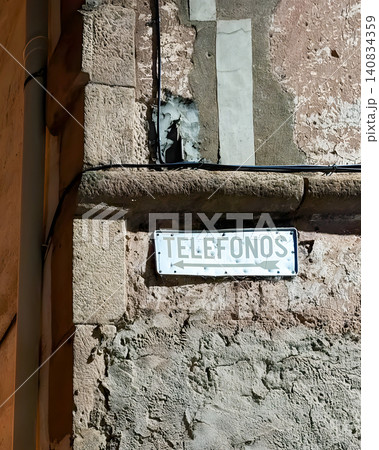 Weathered vintage Telefonos sign on stone wall corner in rural Spanish village Weathered vintage Telefonos sign on stone wall corner in rural Spanish village 140834359