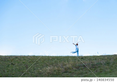 Woman Walking in a Green Field on Rolling Hills, Embracing Freedom and Nature Woman Walking in a Green Field on Rolling Hills, Embracing Freedom and Nature 140834550