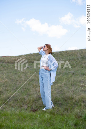 Woman Walking in a Green Field on Rolling Hills, Embracing Freedom and Nature Woman Walking in a Green Field on Rolling Hills, Embracing Freedom and Nature 140834551
