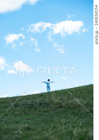 Woman Walking in a Green Field on Rolling Hills, Embracing Freedom and Nature Woman Walking in a Green Field on Rolling Hills, Embracing Freedom and Nature 140834554