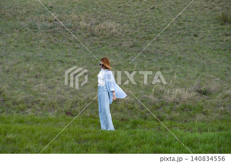 Woman Walking in a Green Field on Rolling Hills, Embracing Freedom and Nature Woman Walking in a Green Field on Rolling Hills, Embracing Freedom and Nature 140834556
