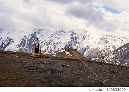 The Gergeti Church of the Holy Trinity is depicted, located against the background of the snow-capped Caucasian Mountains. The Gergeti Church of the Holy Trinity is depicted, located against the background of the snow-capped Caucasian Mountains. 140835009