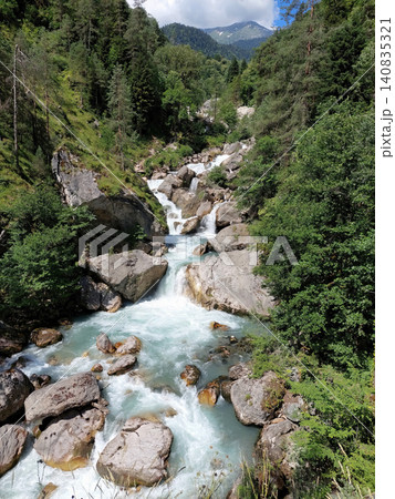 A fast-flowing mountain stream cascading over large boulders in a canyon. 140835321
