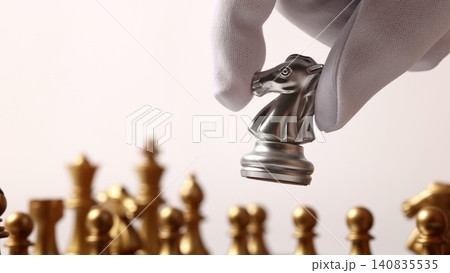 Chess board. Close up chesses strategy concept of silver and gold chess on classic board. Hand carefully moves a piece symbolizing planning decision making leadership competition tactics and success. Chess board. Close up chesses strategy concept of silver and gold chess on classic board. Hand carefully moves a piece symbolizing planning decision making leadership competition tactics and success. 140835535