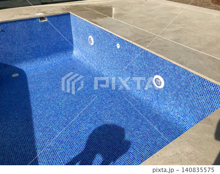 Empty swimming pool with blue mosaic tiles under construction Empty swimming pool with blue mosaic tiles under construction 140835575