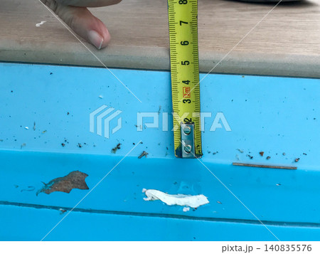 Hand using measuring tape checking pool edge depth Hand using measuring tape checking pool edge depth 140835576