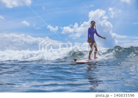 Graceful Young Woman Moves Through Peaceful Waves Beneath Dramatic Sky 140835596
