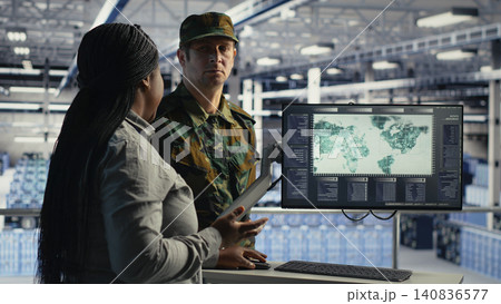 Military technology team reviews a digital world map in a server room to coordinate mission zones with AI support. Military technology team reviews a digital world map in a server room to coordinate mission zones with AI support. 140836577