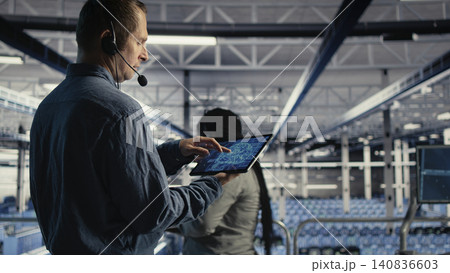 Data center engineer uses tablet in a server room to help clients solve website hosting problems. Data center engineer uses tablet in a server room to help clients solve website hosting problems. 140836603