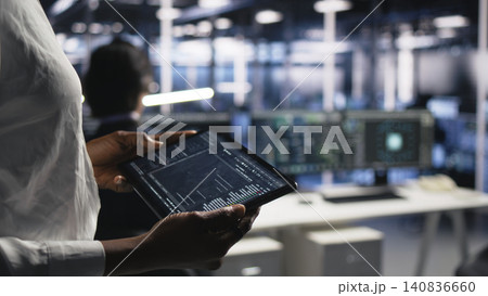 Data center worker monitors system performance and troubleshoots software issues affecting server operations. 140836660