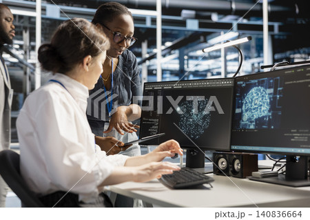 System administrators use a computer in a server hub to visualize AI neural networks and brainstorm system oversight. System administrators use a computer in a server hub to visualize AI neural networks and brainstorm system oversight. 140836664