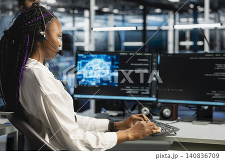 Administrator wears a headset in a server hub, using artificial intelligence troubleshooting to assist users. Administrator wears a headset in a server hub, using artificial intelligence troubleshooting to assist users. 140836709