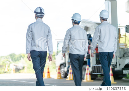 工事現場に向かう作業着の男性スタッフ3人の後ろ姿 工事現場に向かう作業着の男性スタッフ3人の後ろ姿 140837358