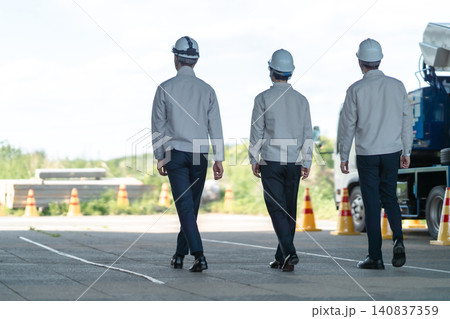 工事現場に向かう作業着の男性スタッフ3人の後ろ姿 工事現場に向かう作業着の男性スタッフ3人の後ろ姿 140837359