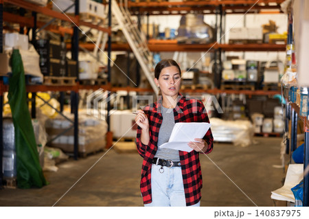 Girl warehouse worker checking inventory Girl warehouse worker checking inventory 140837975